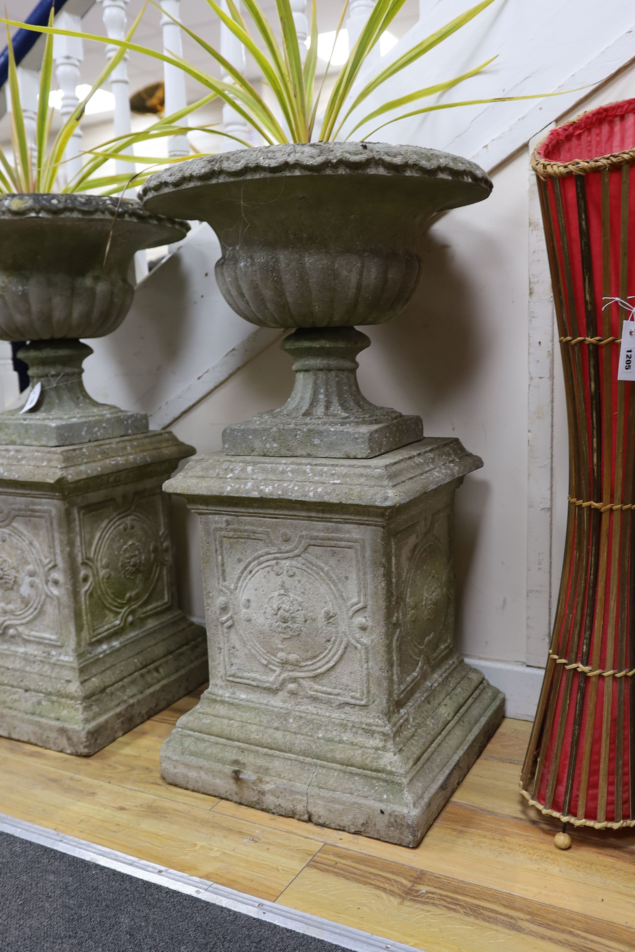 A pair of reconstituted stone campana garden urns on square plinth bases, height 90cm